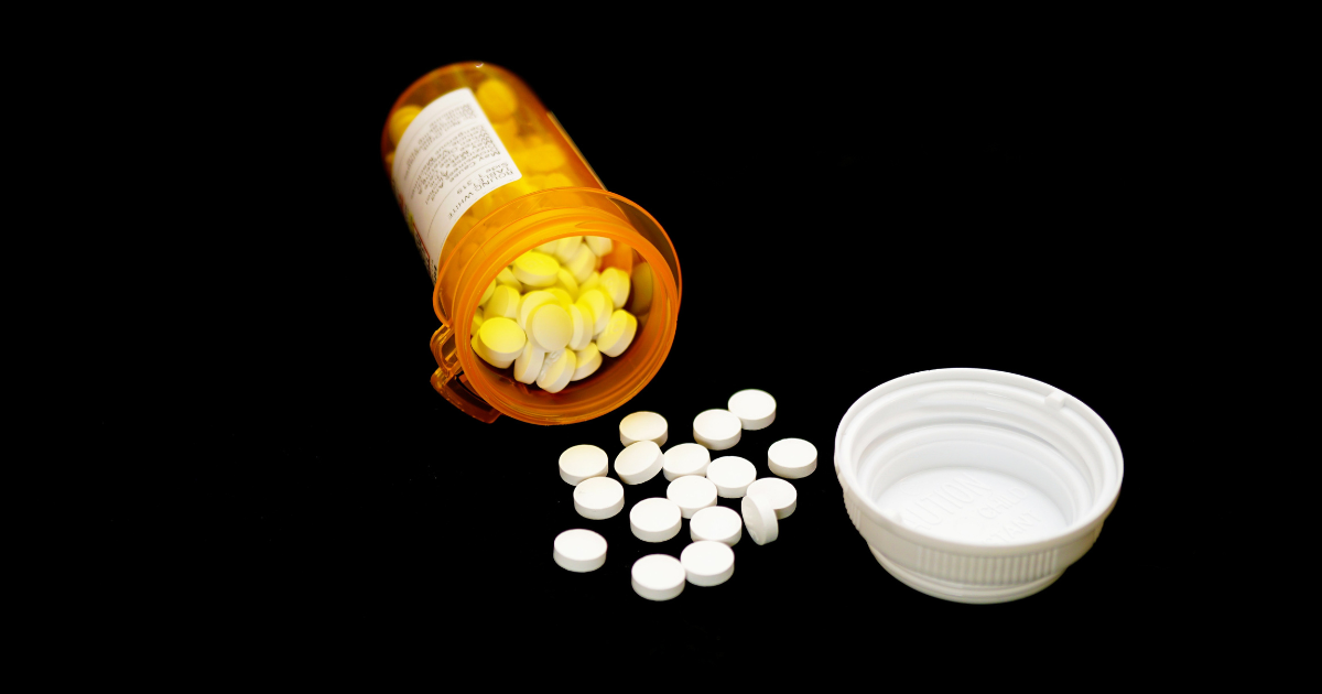 Prescription pill bottle spilled over with white pills, symbolizing the severity of the drug and overdose epidemic.