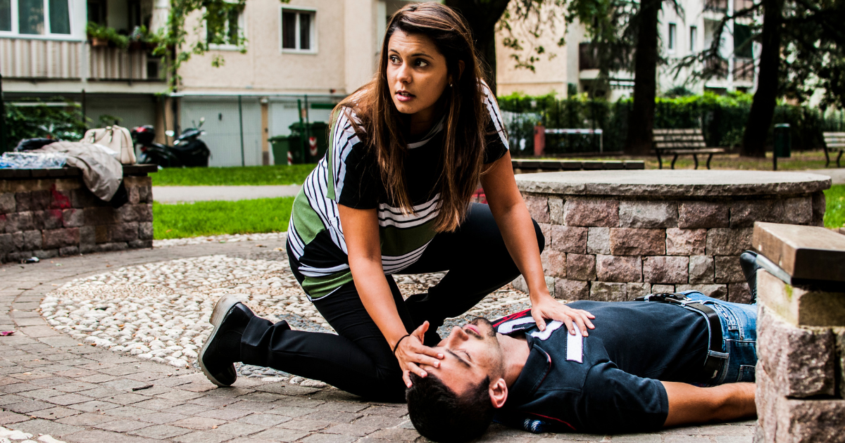 A woman attending to an unconscious individual, illustrating the response to a suspected opioid overdose.