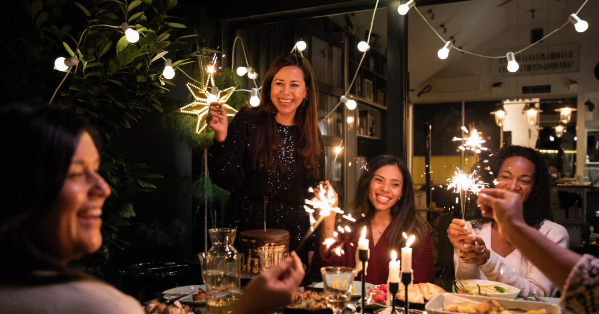 Group of friends celebrating together with sparklers at a festive dinner, enjoying substance-free holiday activities in a supportive setting.